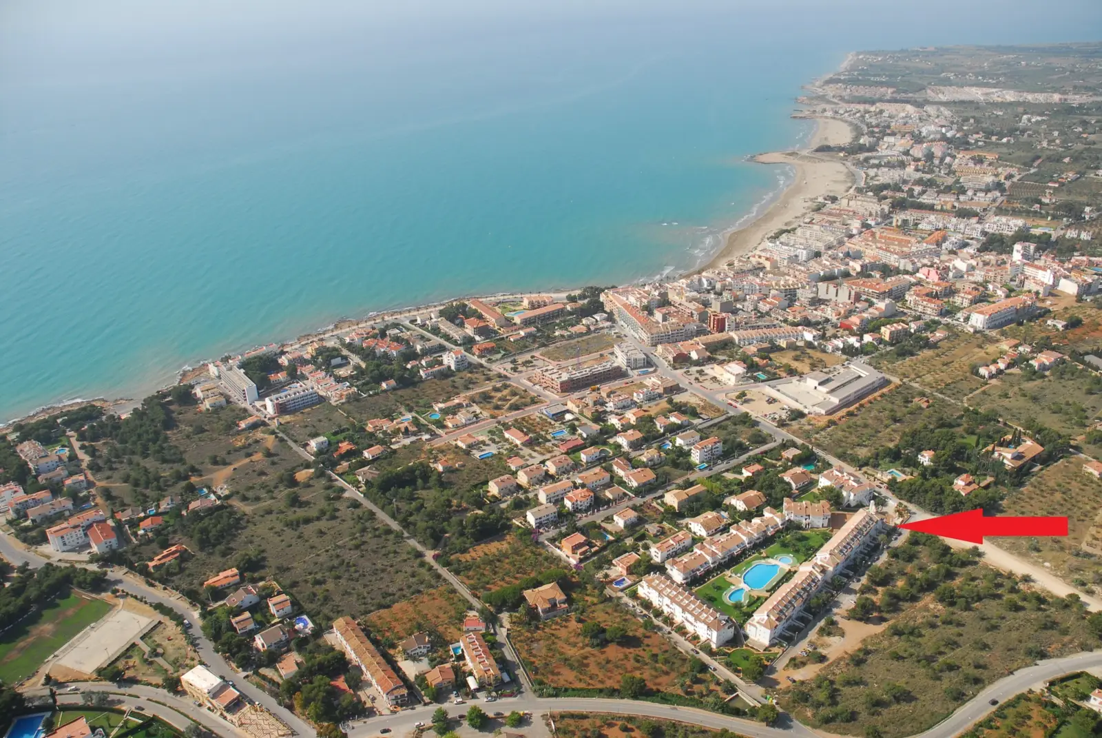 Luchtfoto van Alcossebre met de ligging van het Residencial Al Andalus aangeduid met een pijl en de kust op de achtergrond