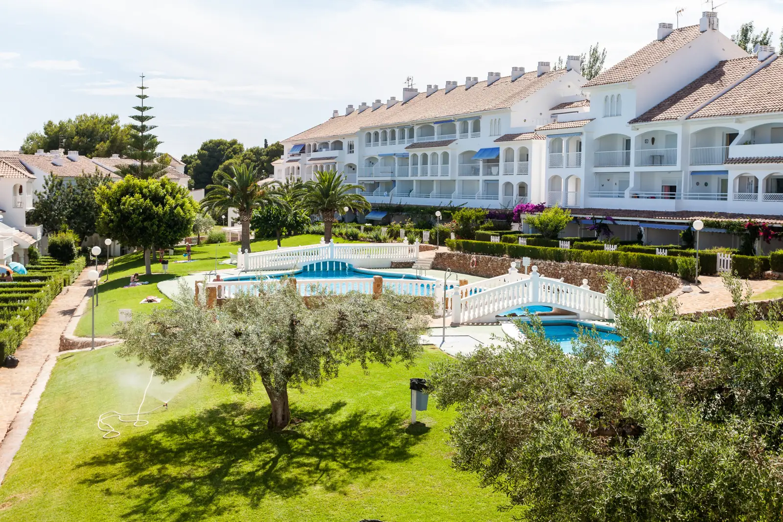 Gesamtansicht der Anlage Al Andalus in Alcossebre: Rasen, Olivenbäume, Pools und weiße Wohnblöcke